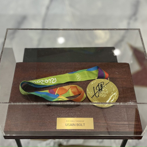 Olympic medal autographed by track and field athlete Usain Bolt, wood