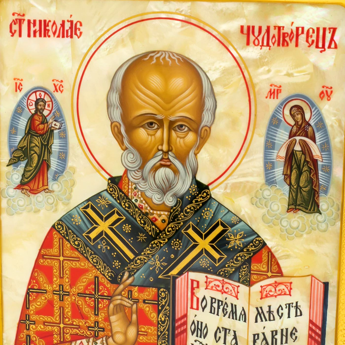 The icon of St. Nicholas the Wonderworker in a kiosk and a gold frame on natural mother-of-pearl